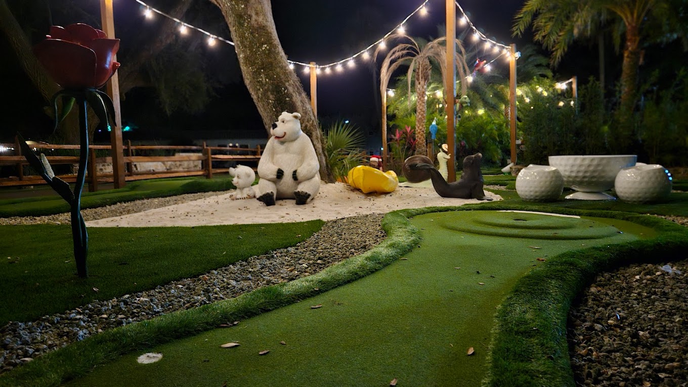 Whimsical mini-golf course lit up at night at Camp Impact
